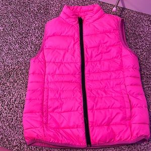 A girls 10/12 puffer vest. A pink puffer vest with black a zipper and pockets.